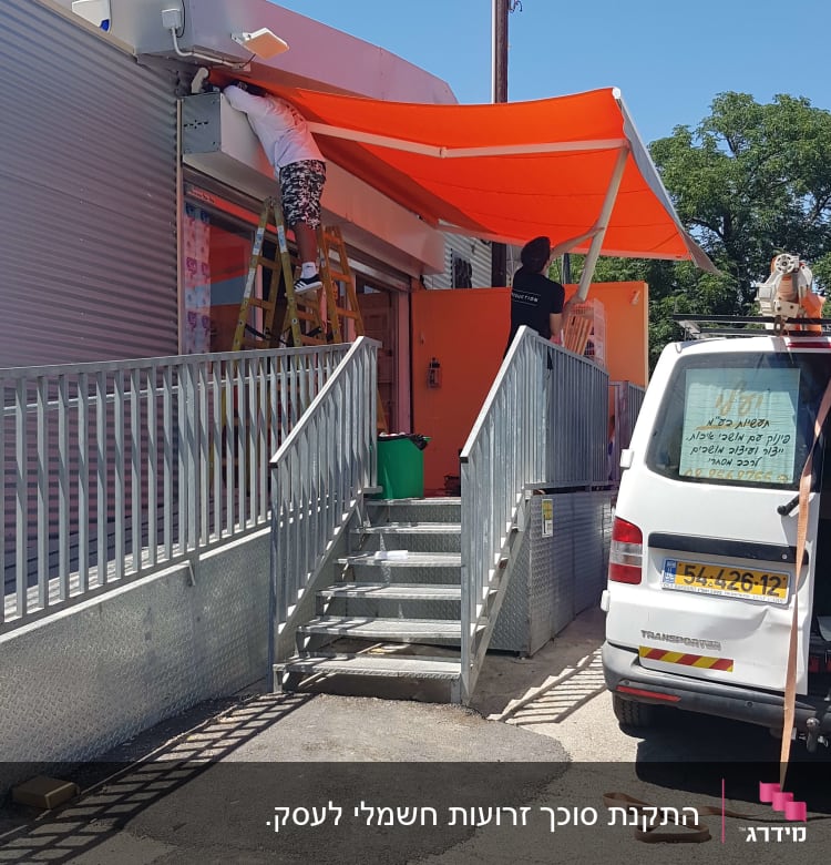 שני אנשים מתקינים סוכך כתום על מבנה